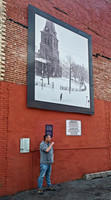Man smoking by large framed print on brick wall