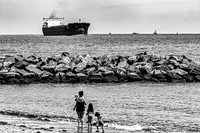 Family Watches Ship Pass By on Water