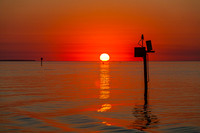 Vibrant Sunset over Calm Waters with Navigational Aid
