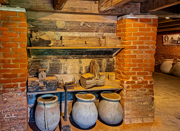 Rustic tools and ceramic pots in historical interior.