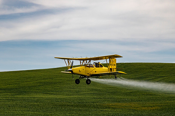 Crop duster spraying fields in Whitman County