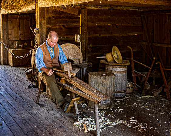 Woodworker using a shave horse in a rustic barn