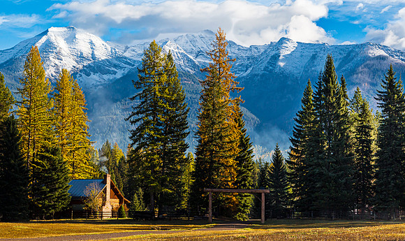 Log Cabin and Snow-Capped Mountains in Autumn