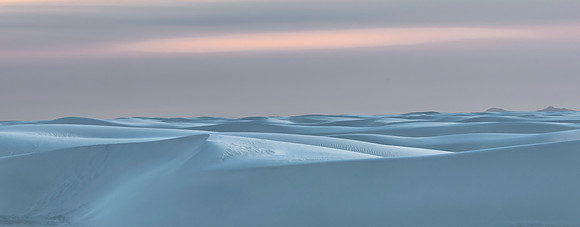 Desert dunes at dawn under pastel sky