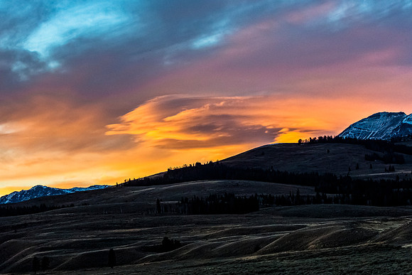Sunset over Rolling Hills and Snow-Capped Mountains