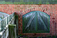 Weathered Fence and Arched Door on Brick Wall